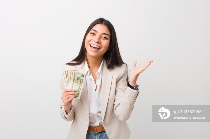 Young arab business woman holding dollars celebrating a victory or success