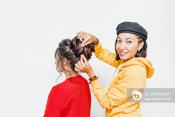 The hands of the professional female hairdresser doing Bridal or evening hairstyle with curls for her client in studio