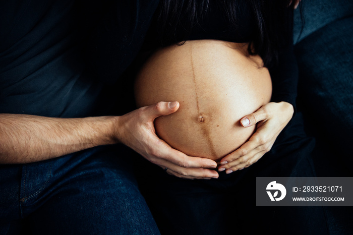 Close up photo shoot of pregnant bump with hands on it.