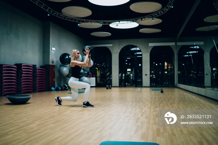 Woman doing lunges with medicine ball in gym