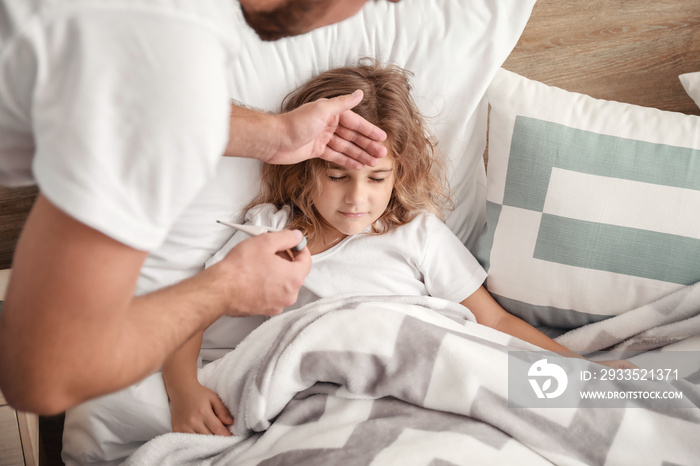 Father measuring temperature of his little daughter ill with flu at home