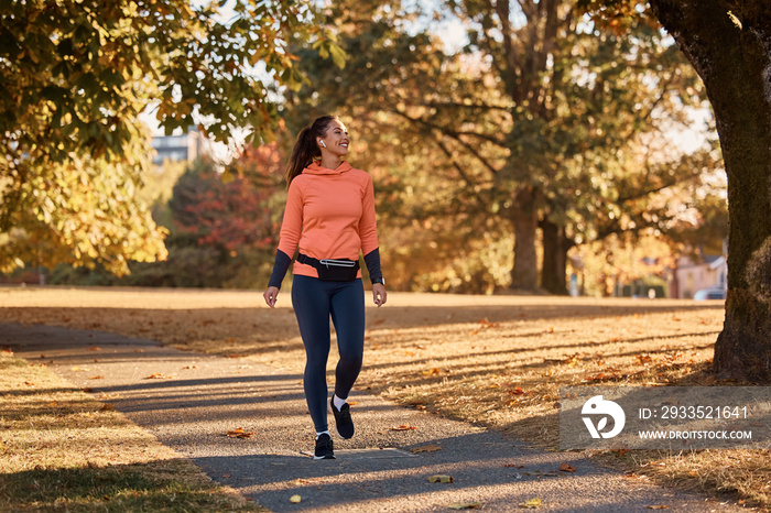 Happy athletic woman taking a walk through autumn park.