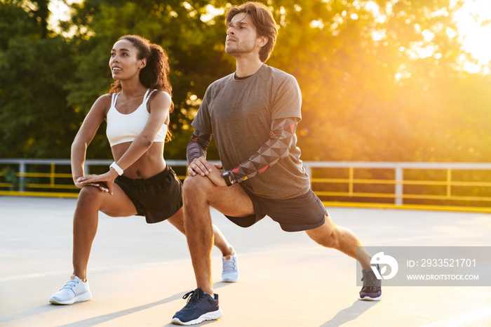 Photo of strong young couple stretching their legs together