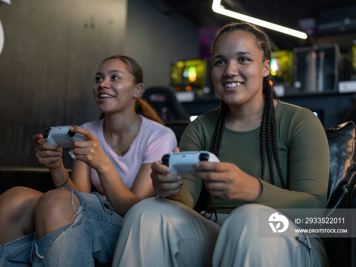 Female friends playing video games in gaming club