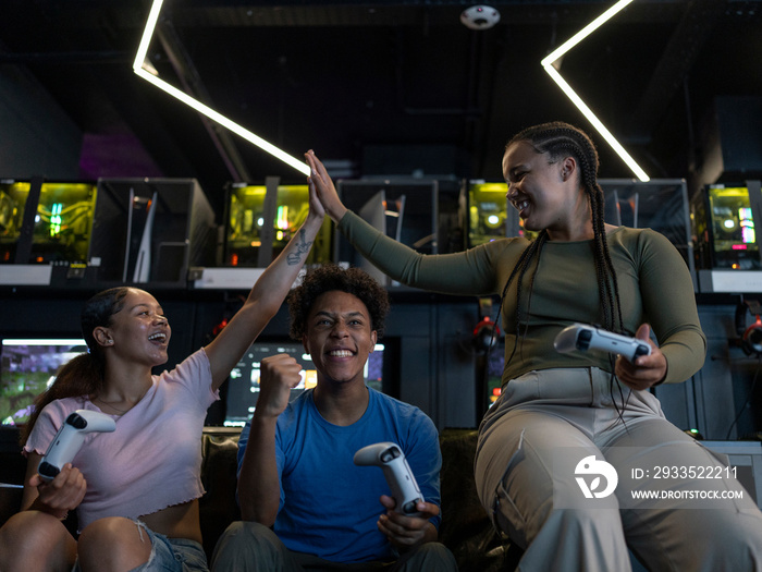 Excited friends playing video games in gaming club