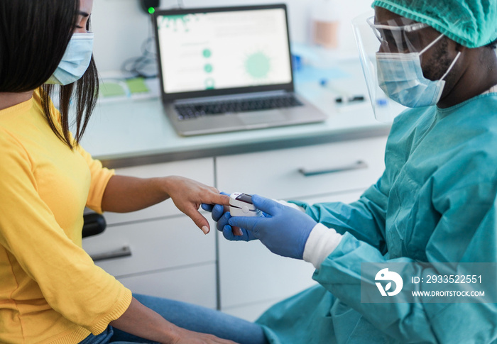 African male doctor using pulse oximeter on woman patient finger while wearing surgical face masks for coronavirus outbreak - Measuring oxygen saturation