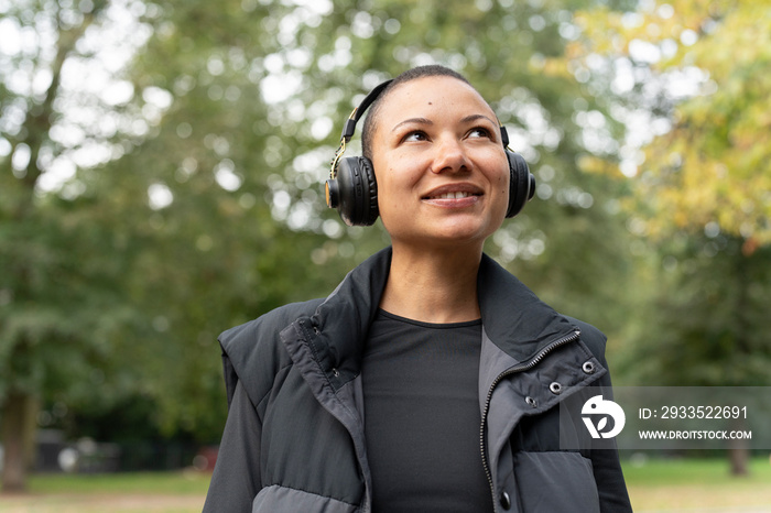 Portrait of smiling woman in sports clothing and headphones in park