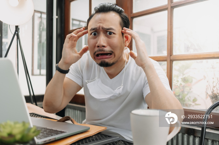 Crying and shocked funny face of Asian man disappoint his work in his laptop.