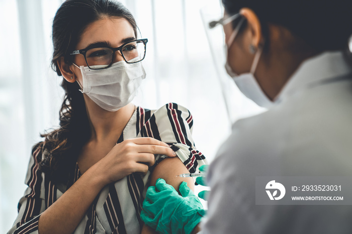 Young woman visits skillful doctor at hospital for vaccination . Covid 19 and coronavirus vaccination center service concept .