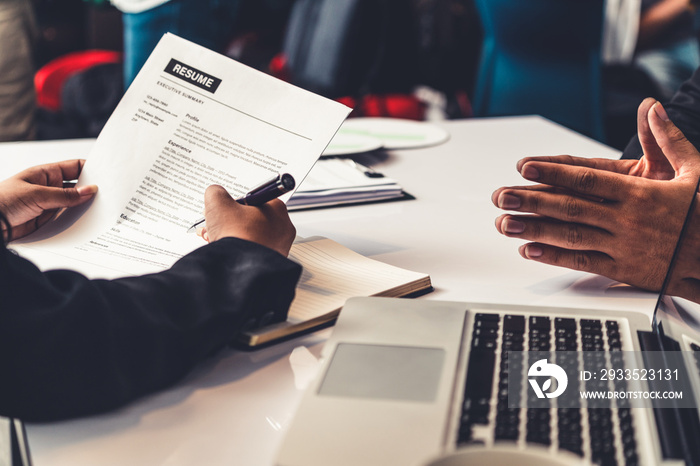 Human resources department manager reads CV resume document of an employee candidate at interview room. Job application, recruit and labor hiring concept.