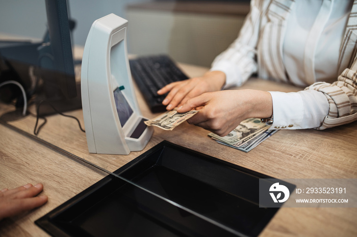 Businesswoman is working in exchange office. She is giving cash money to male customer.