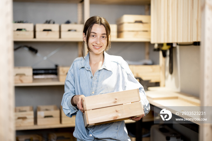 Portrait of a young handywoman holding wooden toolbox in the workshop. Concept of organization in home workshop or storage