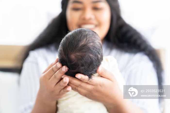 Mother carrying her newborn baby. Happy mum holding infant child on her hands