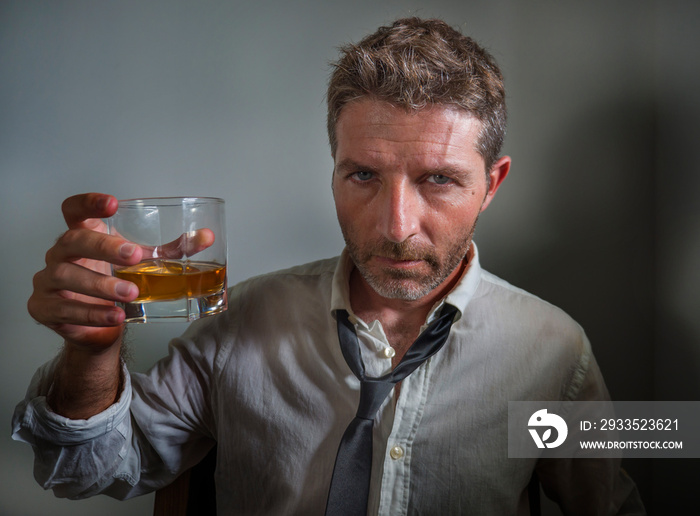 portrait of 30s to 40s alcoholic  man in lose necktie drinking desperate holding whiskey glass thoughtful drunk and depressed completely wasted in alcohol addiction concept