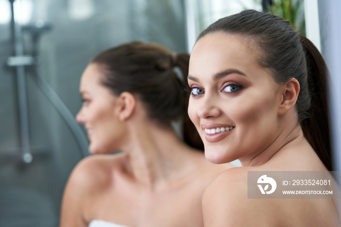 Woman looking on reflection in the mirror after shower