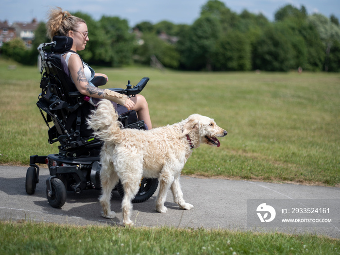 Woman in electric wheelchair going on walk with dog