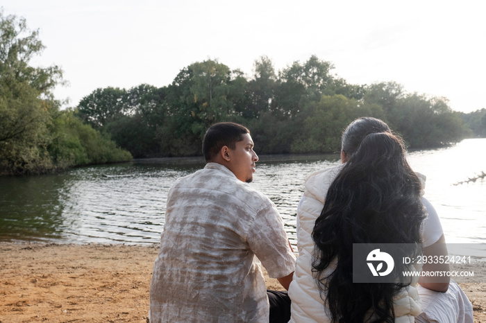 Rear view of couple sitting on lakeshore