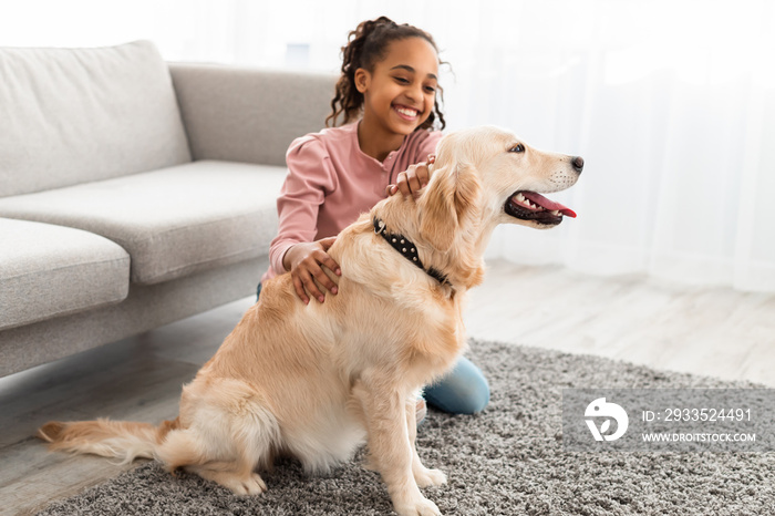 Young afro girl having fun with dog at home