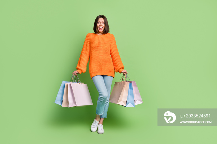 Full length body size view of attractive cheerful girl holding new things having fun isolated over bright green color background