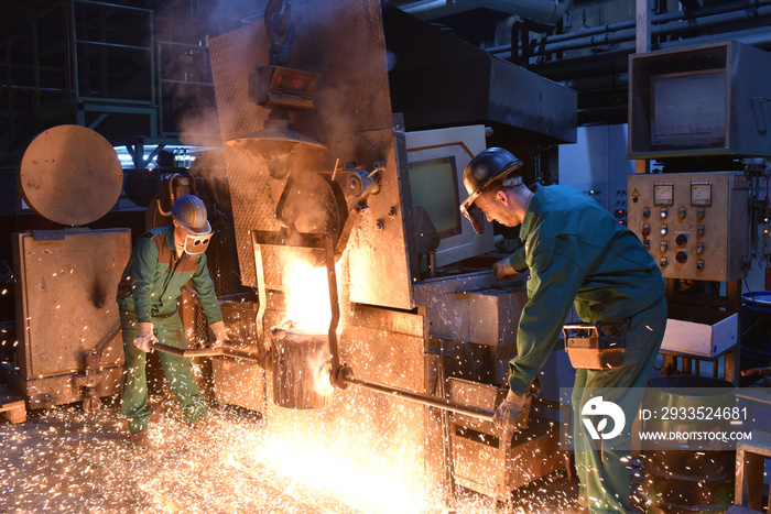 workers in a foundry casting a metal workpiece - safety at work and teamwork