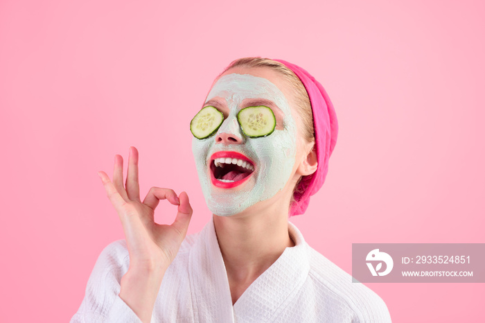 Close-up portrait of beautiful woman with facial mask. Spa salon. Cosmetic mask with cucumber. Natural beauty. Perfect skin. Woman with cucumber slices on eyes. Wellness and Spa concept. Sign okay.