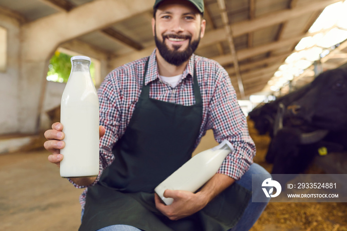 Happy farmer demonstrating bottles of fresh natural milk manufactured on his buffalo farm