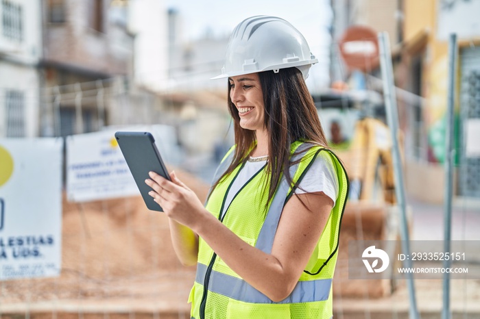 Young beautiful hispanic woman architect smiling confident using touchpad at street