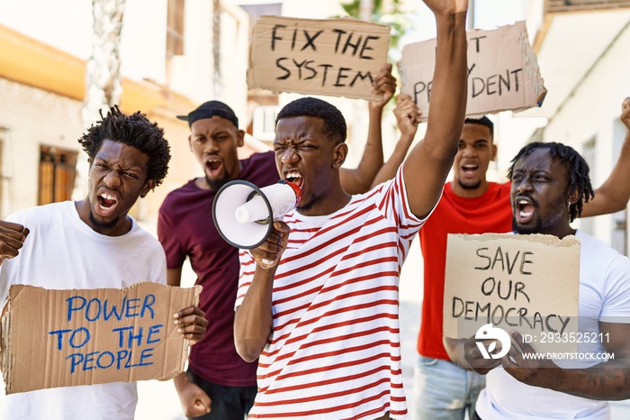 Group of young african american activists protesting holding banner and using megaphone at the city.