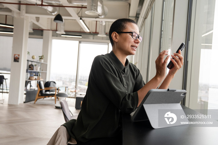 Woman using digital tablet and phone in office