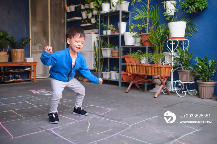 Active cute smiling Asian toddler boy having fun jumping, playing hopscotch at home, Hopscotch helps children to manage body rhythm, movements, build body strength, balance, Play and Grow concept