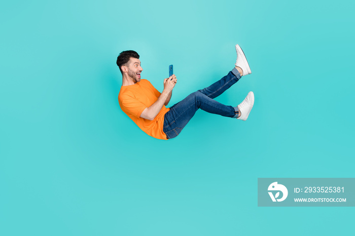 Full body photo of guy blogger falling downward using device incredible news sale isolated on cyan color background