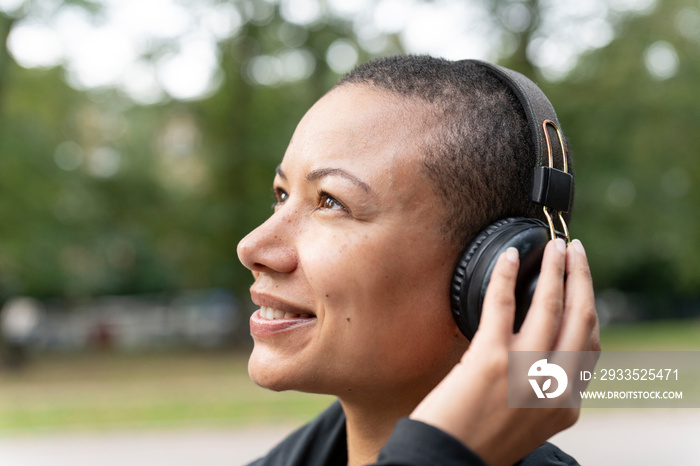 Close-up of smiling woman with headphones in park