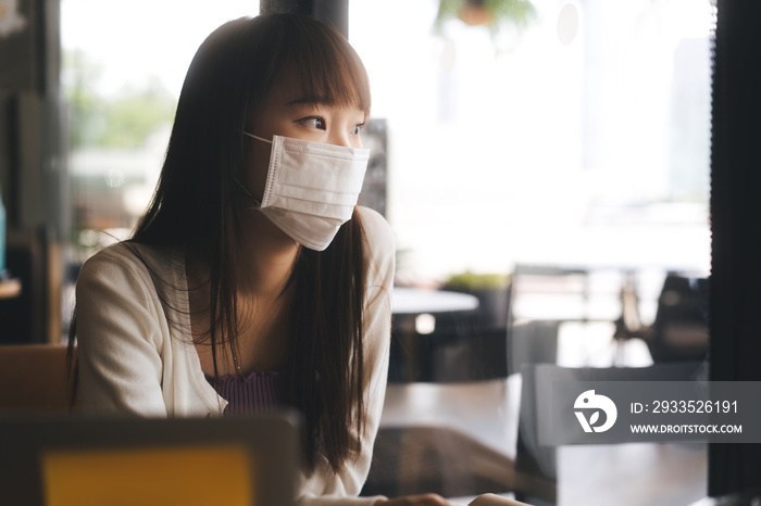 Young adult asian student female with face mask for virus corona or covid 19 study at cafe.