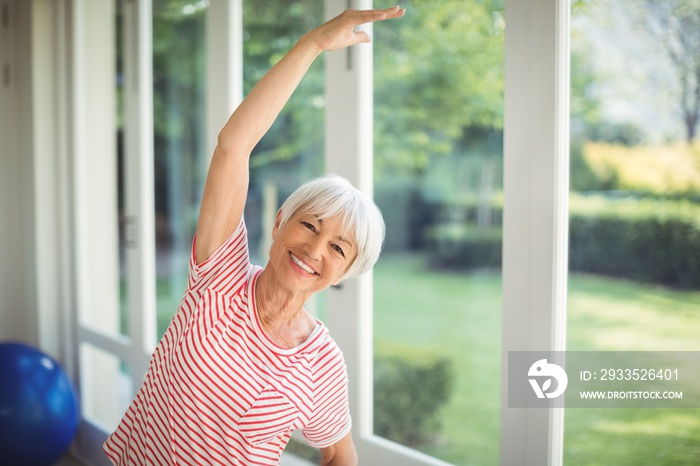 Portrait of senior woman performing stretching exercise at home