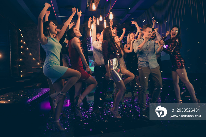 Full length body size photo of cheerful charming beautiful young people having fun at night club dancing in falling confetti rain standing under lights