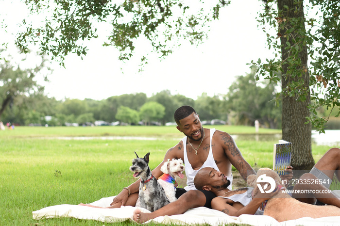 USA, Louisiana, Gay couple with dogs relaxing on lawn in park