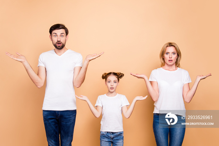 Portrait of young family bieng confused, bearded father, blonde mother and their little daughter wearing jeans and T-shirts, showing uncertain gesture with their hands