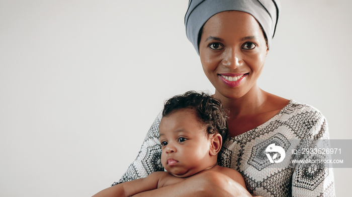 portrait of african american mother holding her baby girl isolated on white, black female cancer patient in healing with chemotherapy holding her baby on hands