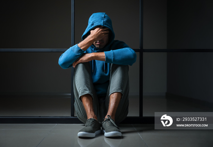 Depressed male junkie sitting on floor