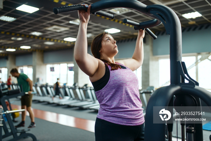 Overweight woman on exercise machine in gym