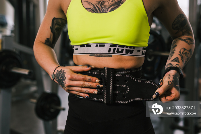 young woman workout in gym, putting belt for power lifting