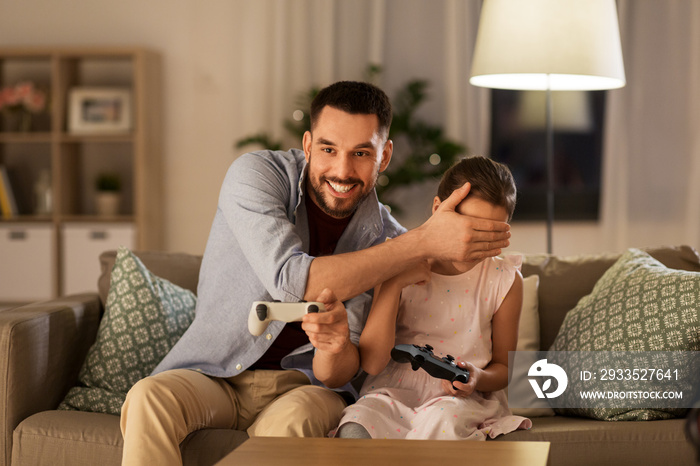 family, gaming and entertainment concept - happy father and little daughter with gamepads playing video game at home