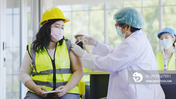 COVID-19 Vaccination station in construction industry. Doctor are vaccinating to group engineer worker protect COVID-19 or flu in hospital. People wear face mask protection from virus. health welfare