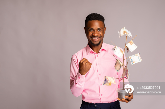 man feeling excited as he holds money tree