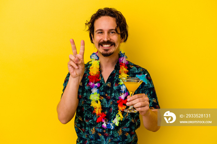 Young caucasian man wearing a hawaiian necklace holding a cocktail isolated on yellow background showing number two with fingers.