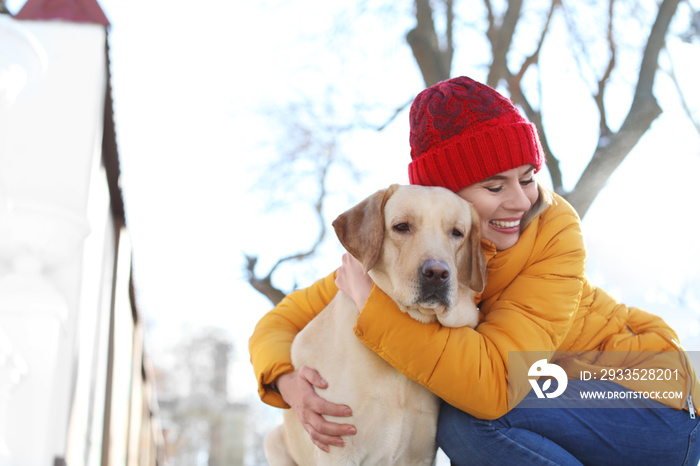 Woman hugging cute dog outdoors on winter day. Friendship between pet and owner