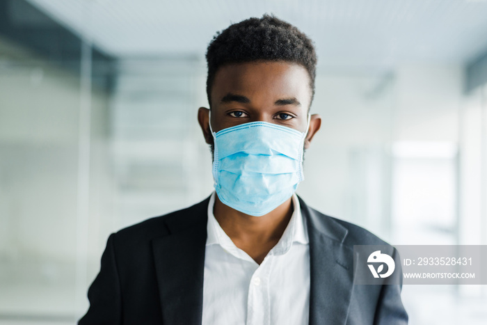 Young african man in medical mask on his face in office