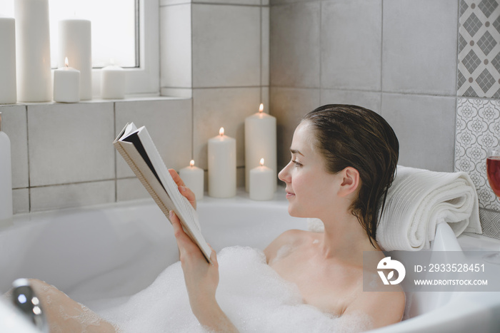 Young woman relaxes in a hot bath full of foam.