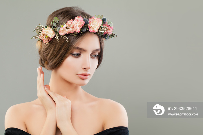 Pretty young woman wearing flowers wreath on gray banner background