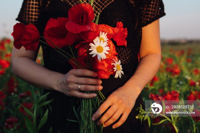 bouquet of poppies flowers in woman hand on sunset